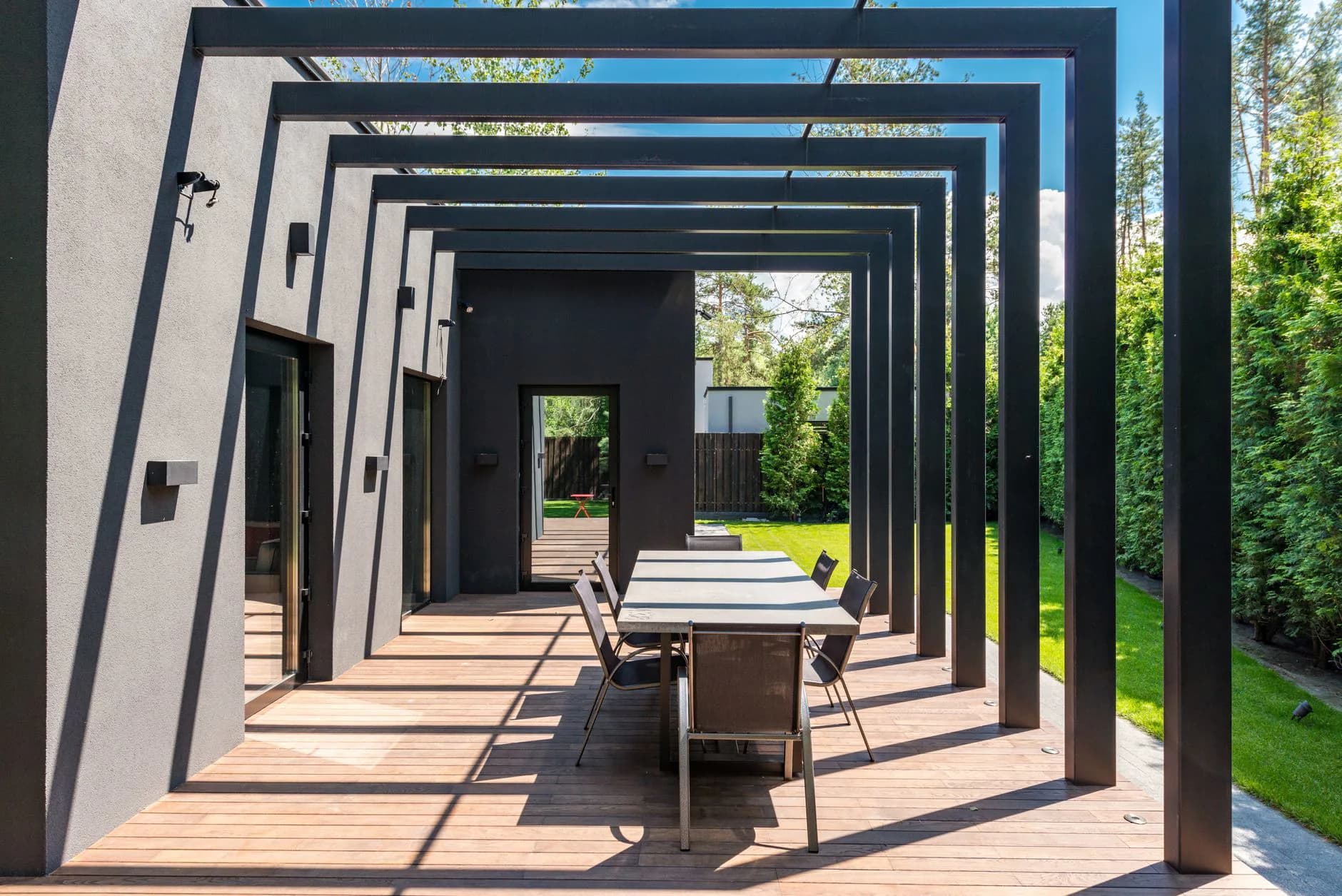 A wooden pergola over a patio, its rafters casting striped shade