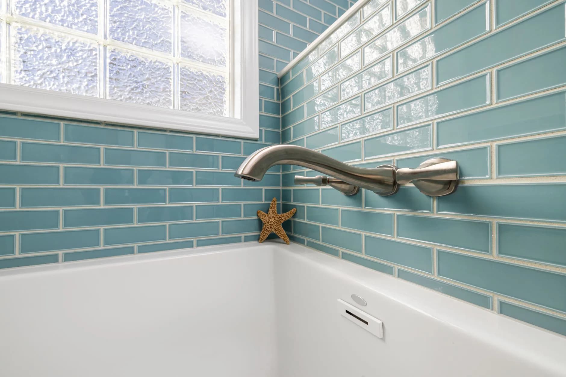 A tiled bathroom wall with its grout lines and fixtures