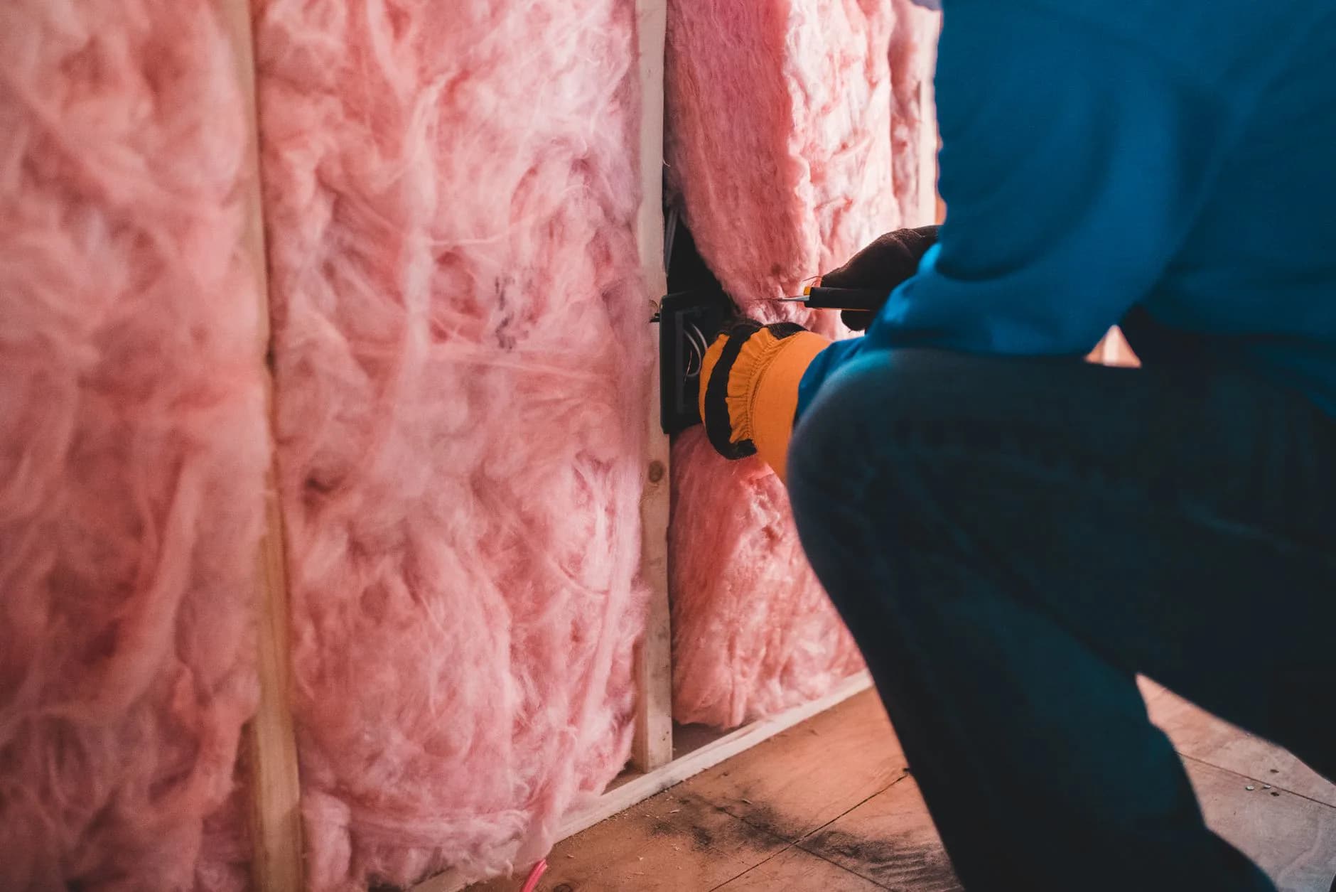 A worker insulating an open wall cavity