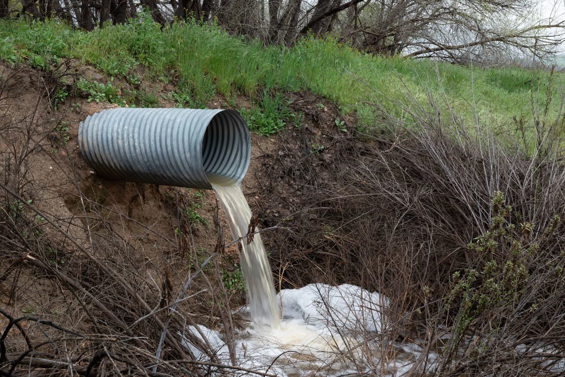 A drain pipe discharging water onto open ground