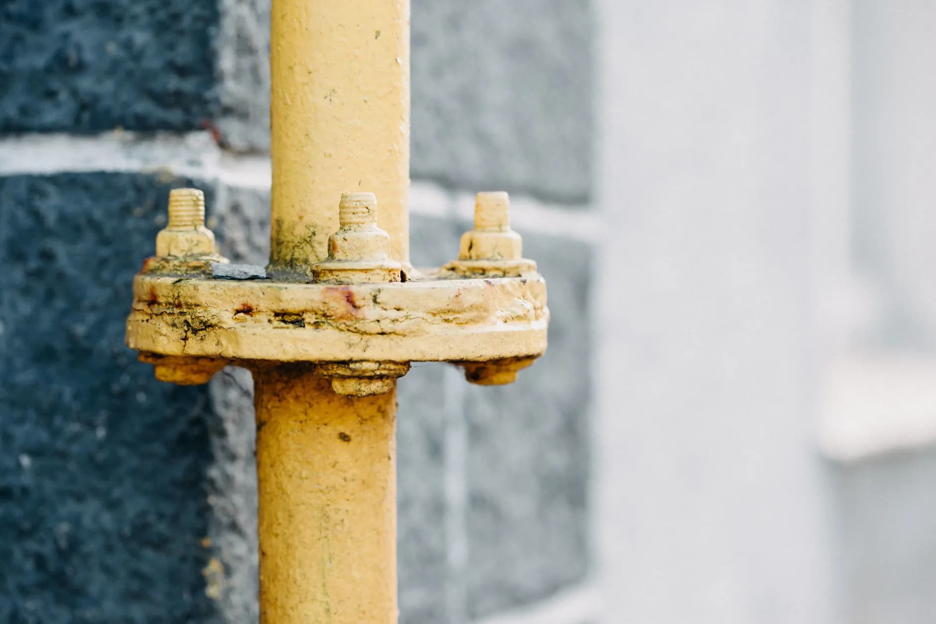 A yellow gas pipe against a wall