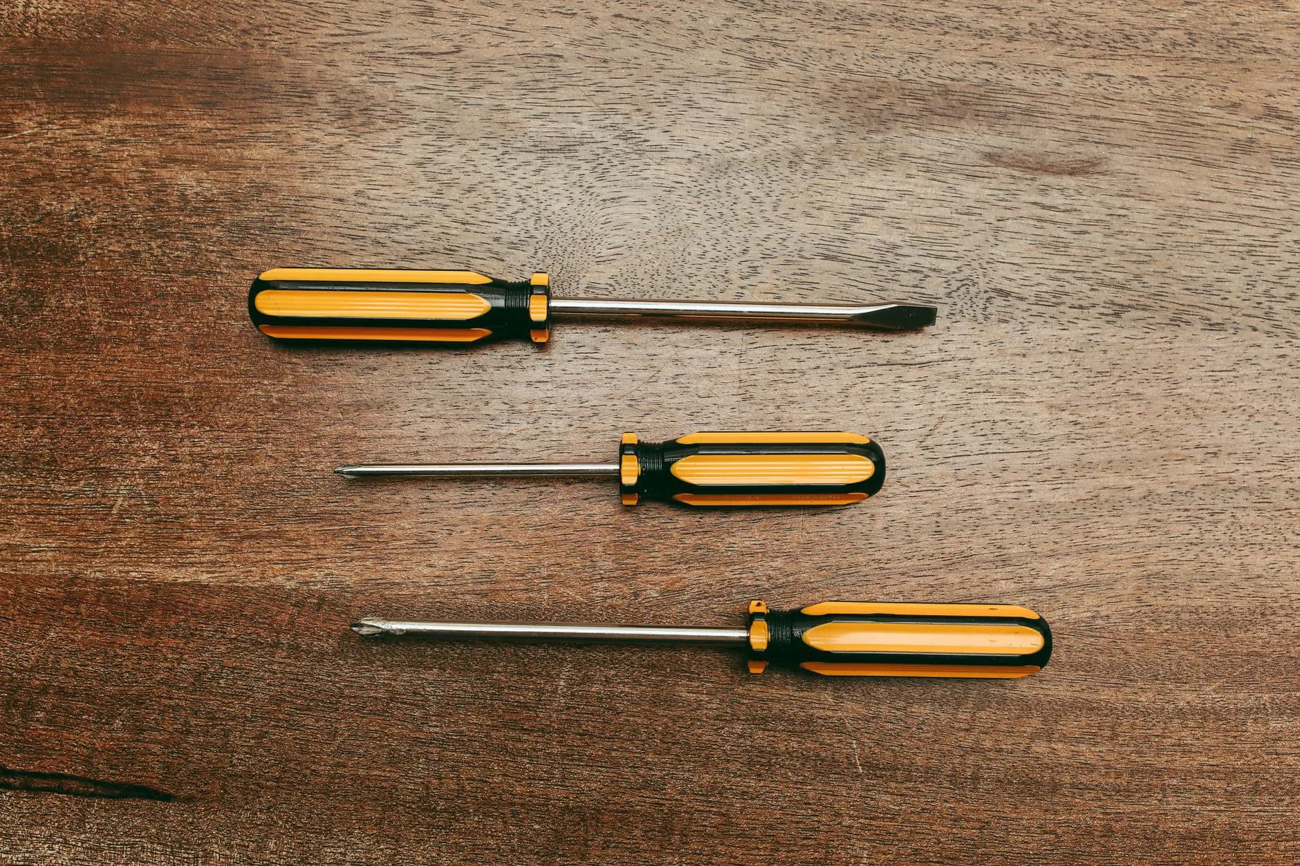 A screwdriver being pushed into wood