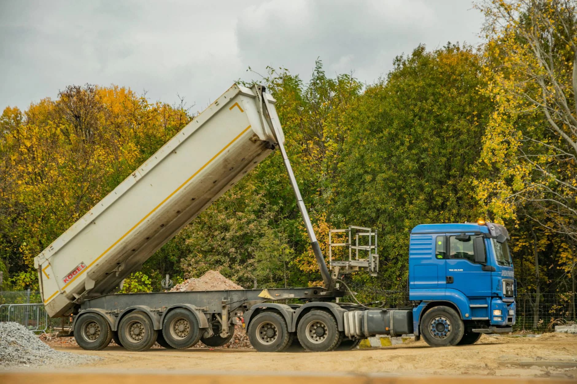 A dump truck tipping a load of soil at a residential site
